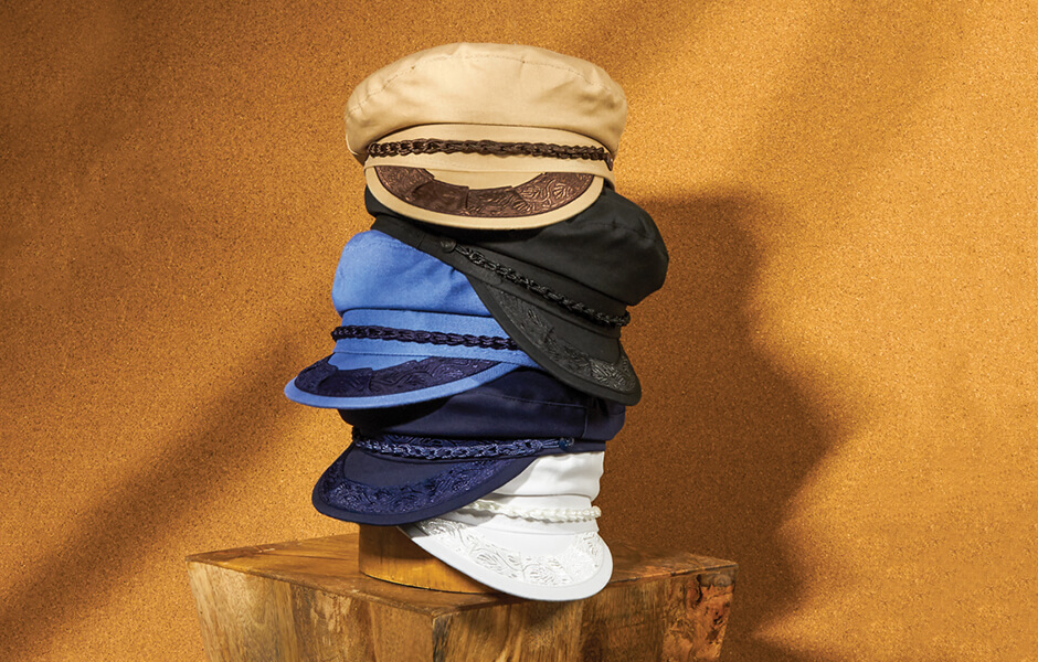 A stack of 5 Aegean hats displayed on a hat block on a wooden desk